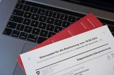 Ausschnitt eines Schweizer Stimmzettels von 2023, der auf einer Laptop-Tastatur liegt.