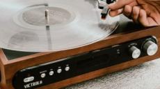 Nahaufnahme eines alten Plattenspielers, bei dem gerade die Nadel auf eine Schallplatte gesetzt wird.