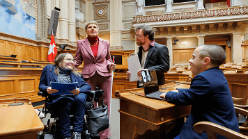 Vier Personen mit einer Behinderung sind im Bundeshaus und diskutieren.