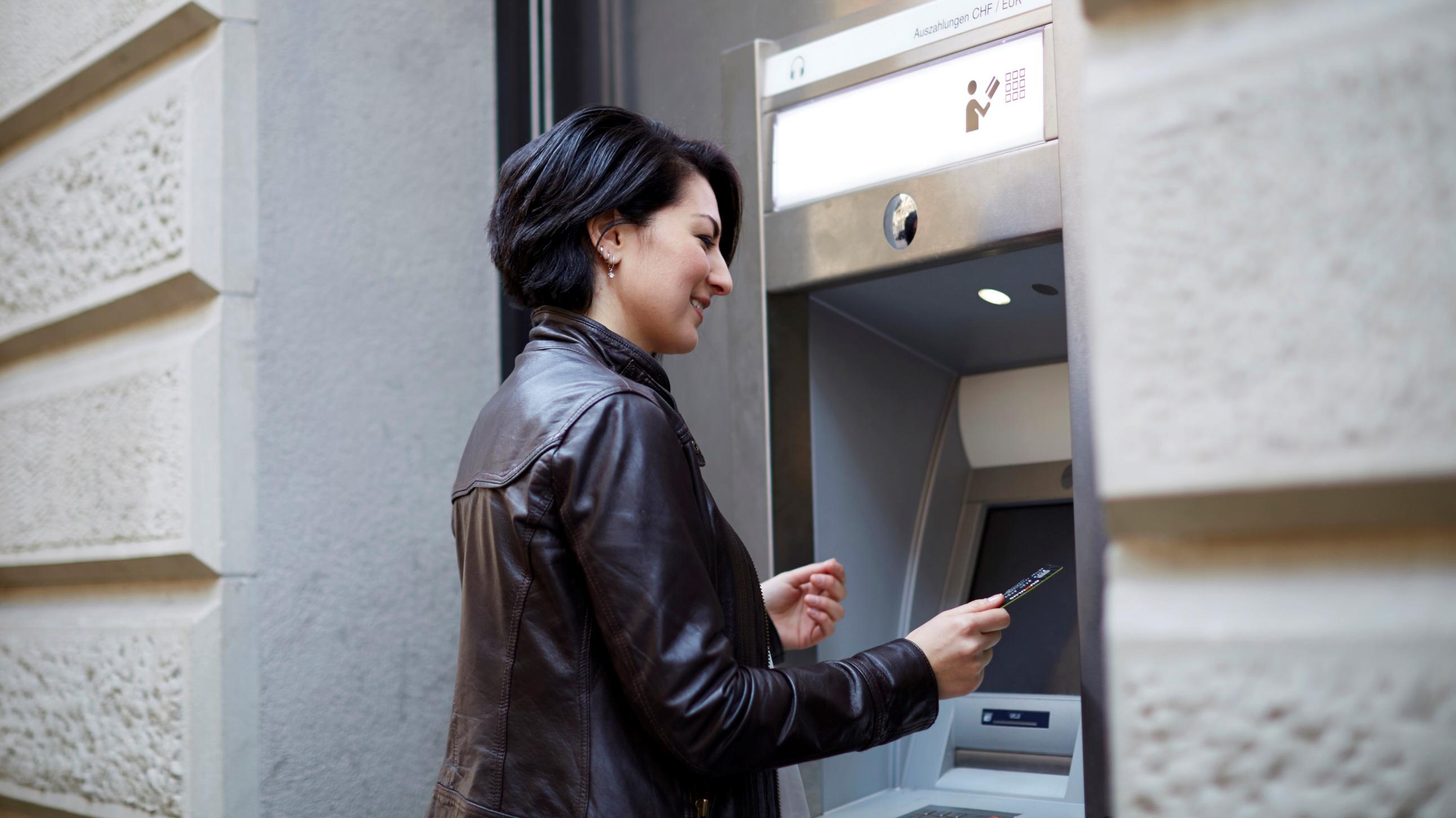 Eine Frau steht vor einem Geldautomaten.